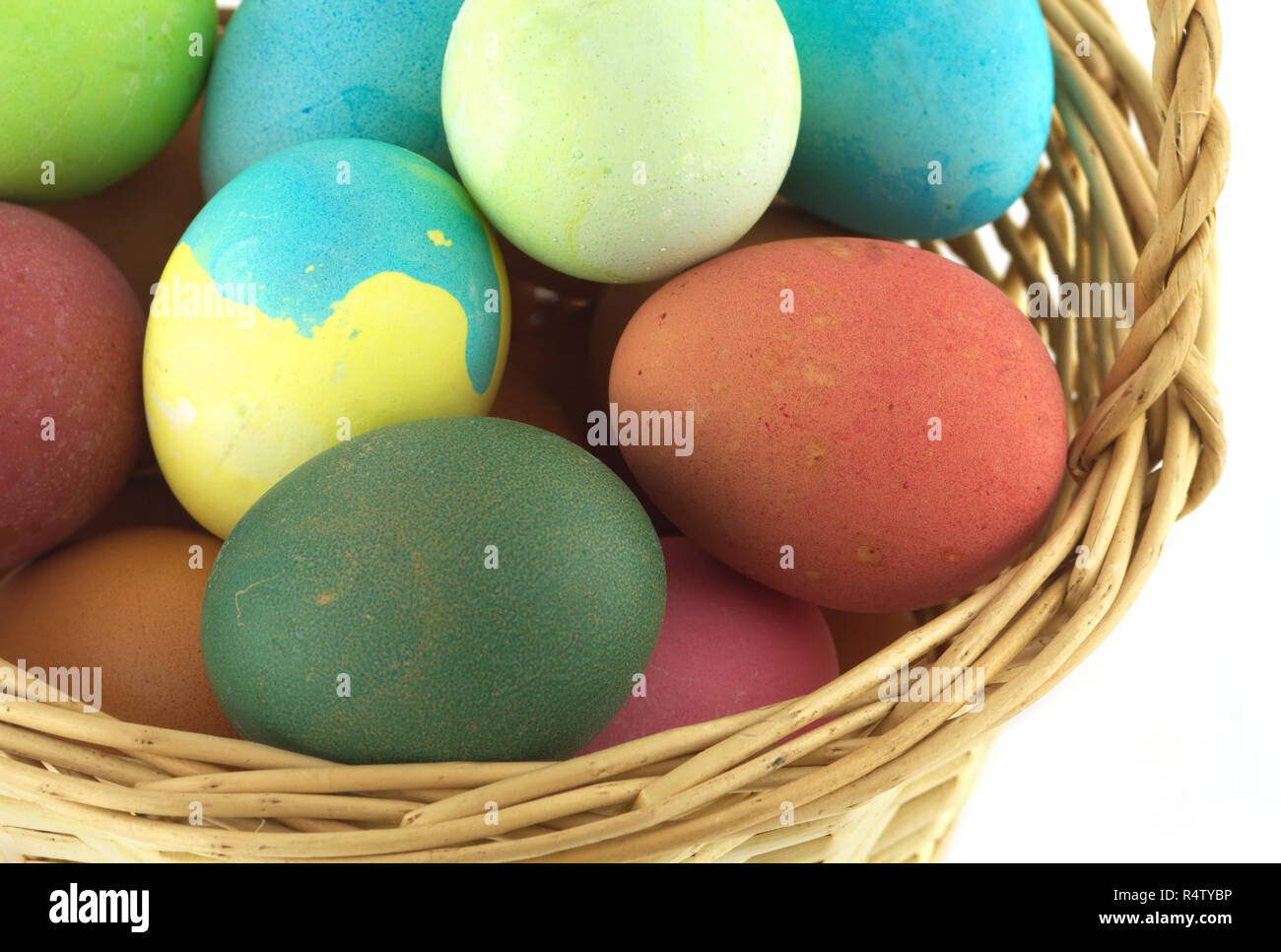 Colorful Easter eggs inside straw wicker brown basket isolate on white closeup Stock Photo