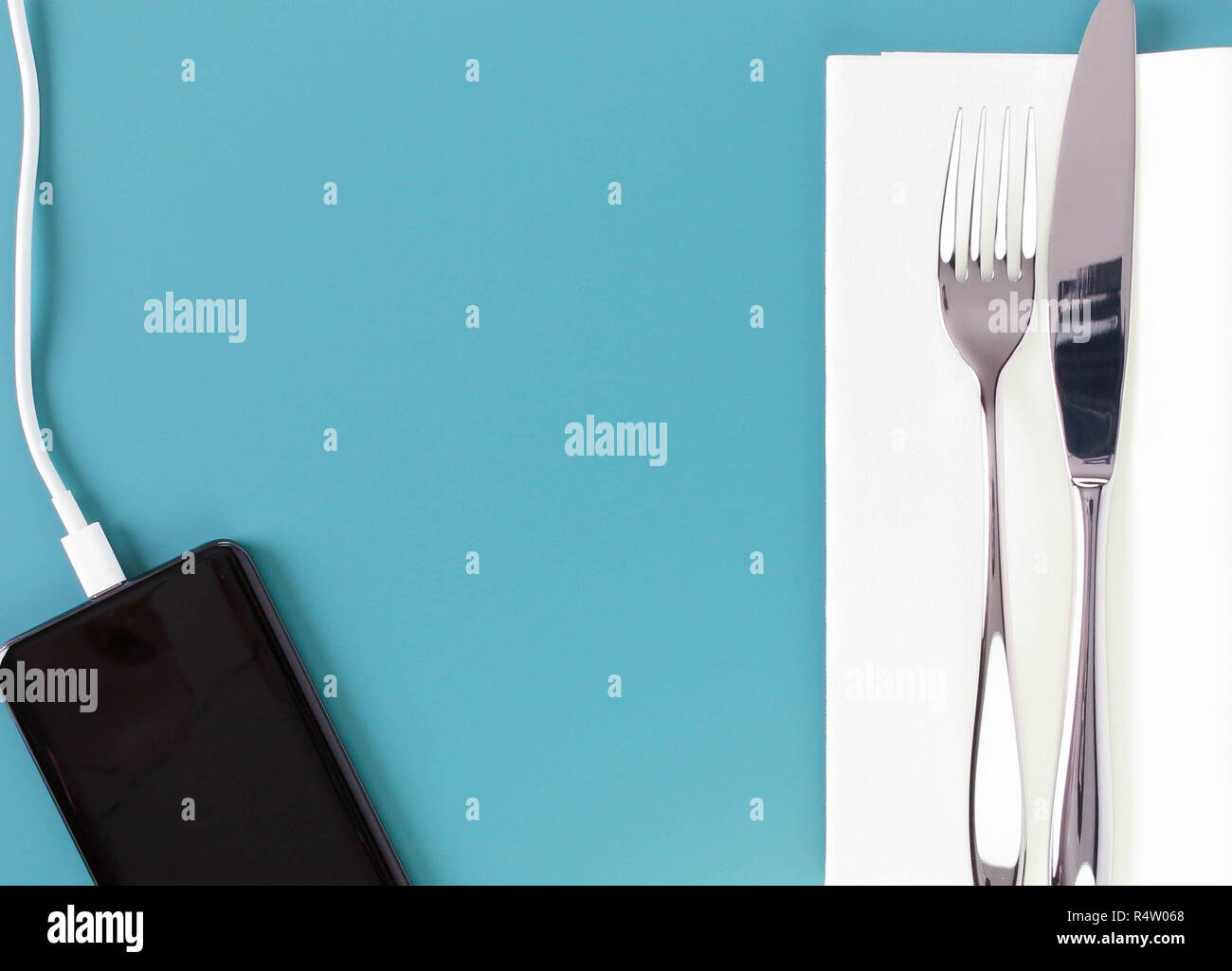 Mobile phone charging with cutlery at airport restaurant Stock Photo