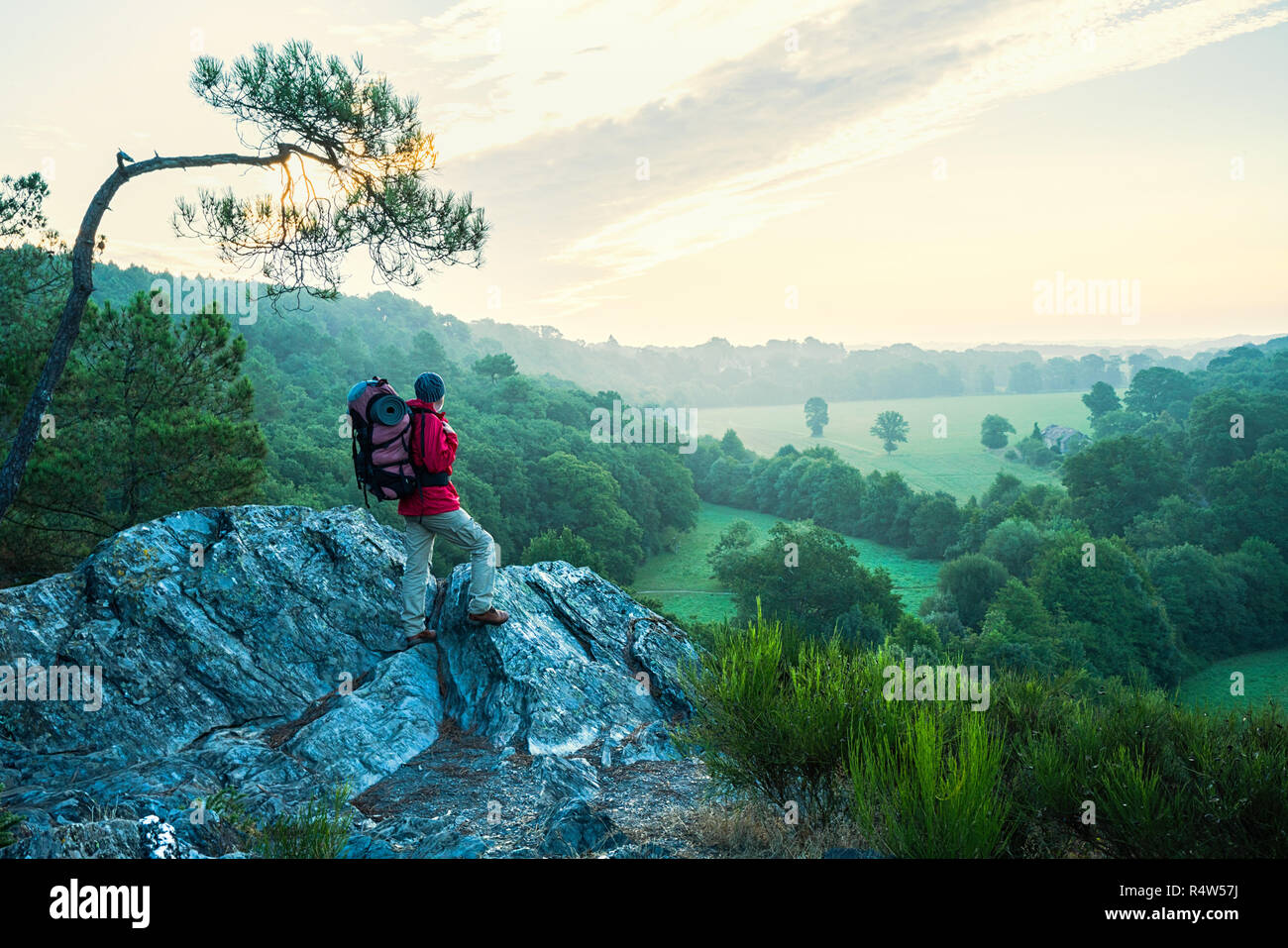 A man hiking on a mountain trail looks down the valley Stock Photo
