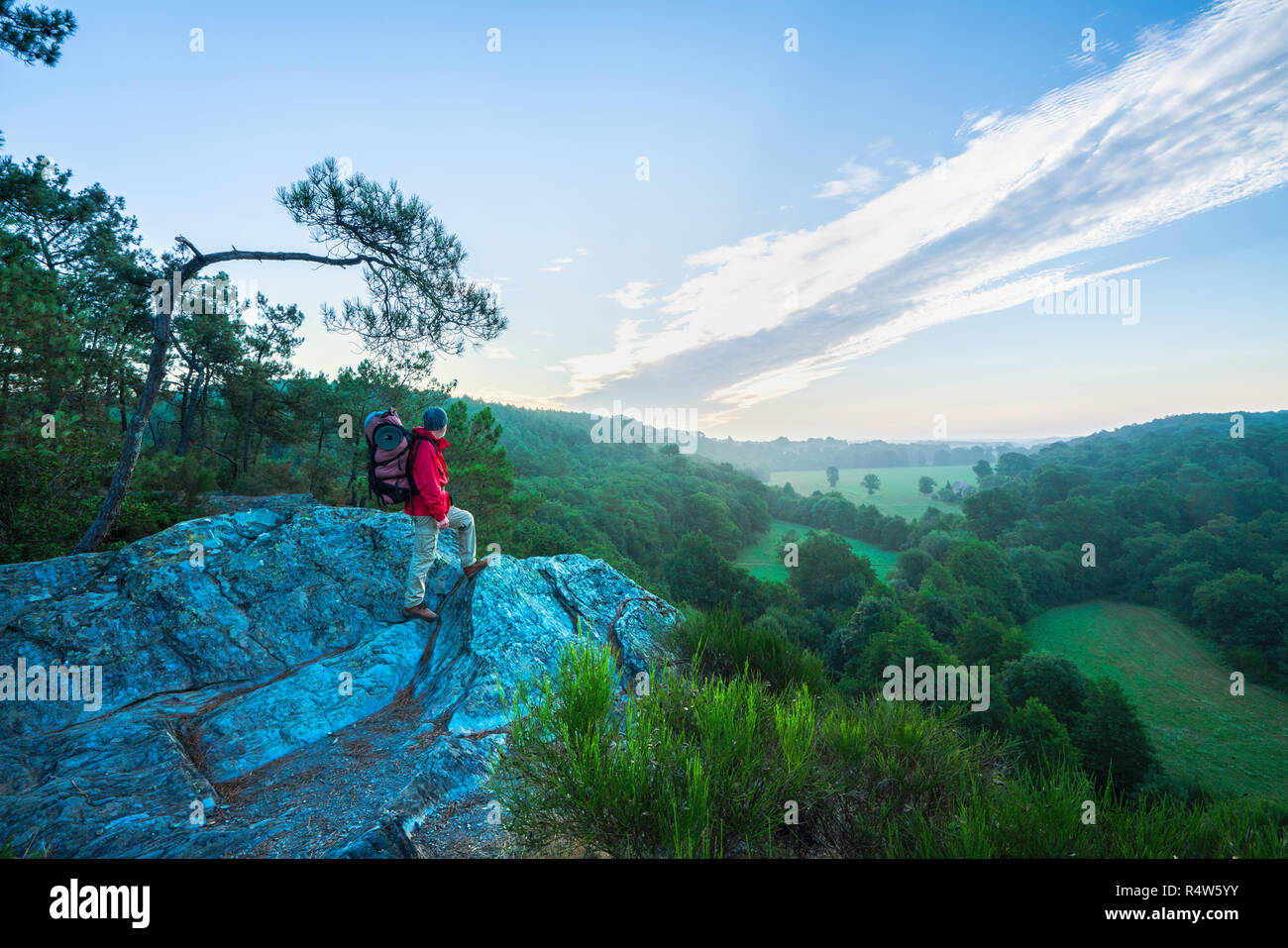 A man hiking on a mountain trail looks down the valley Stock Photo