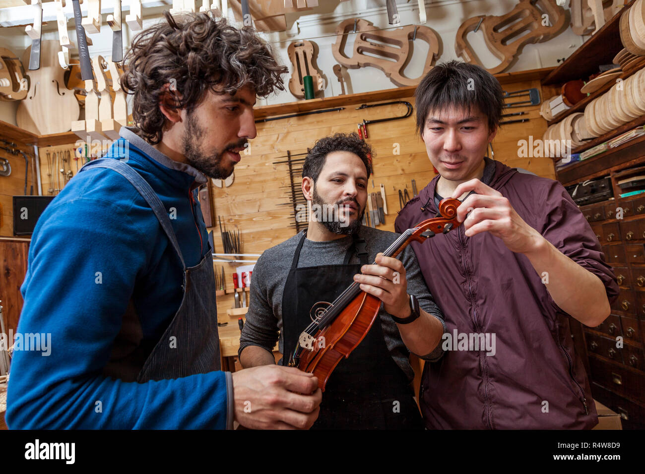 group of craftsmen violinmakers testing a new violin in their
