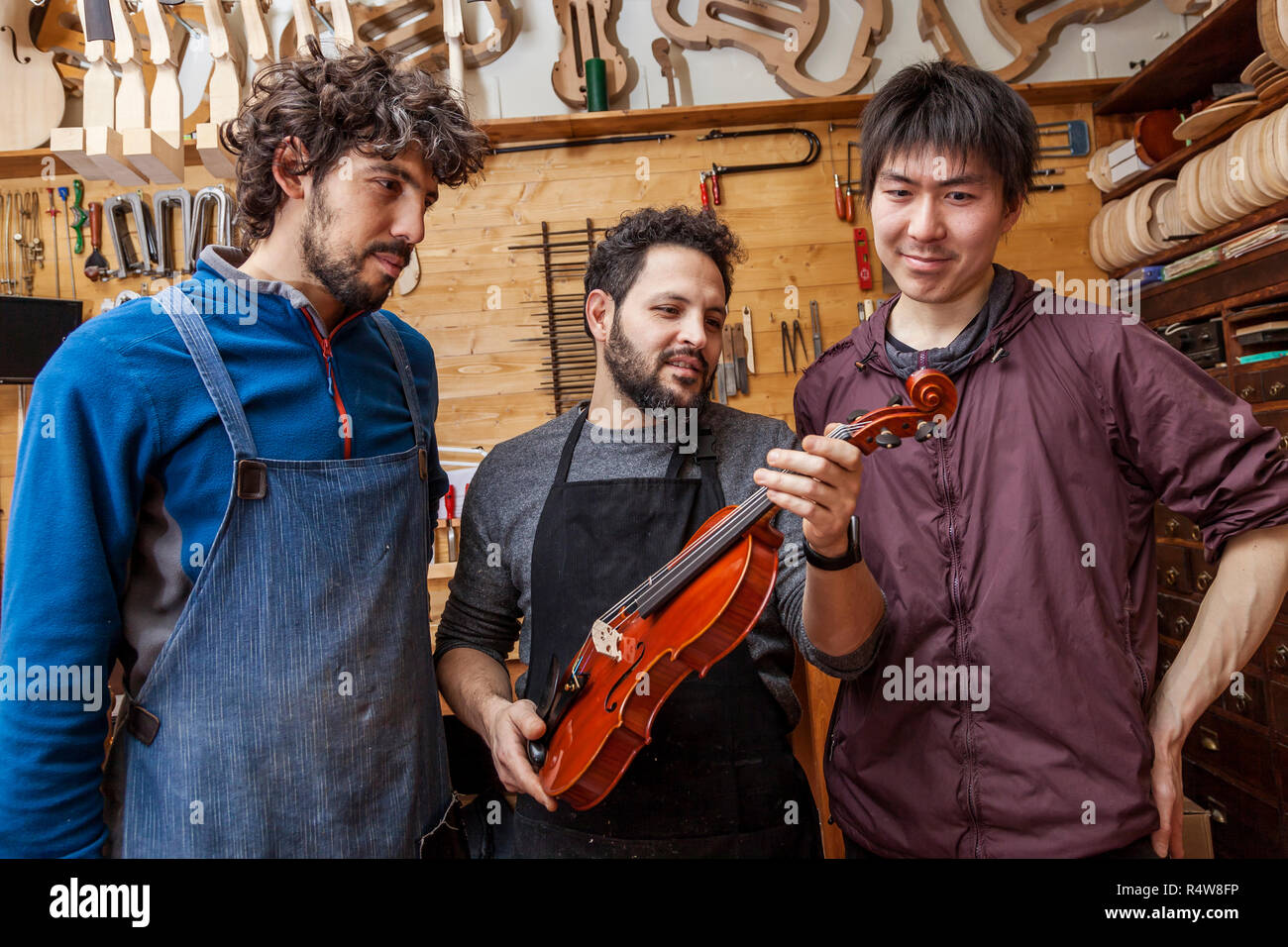 Group Of Craftsmen Violinmakers Testing A New Violin In Their