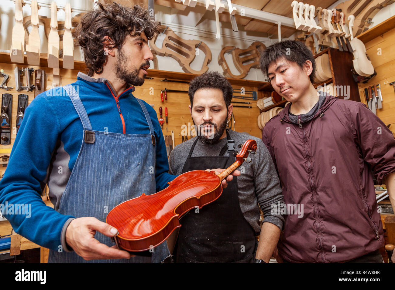 group of craftsmen violinmakers testing a new violin in their