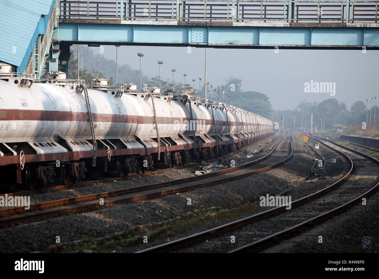 A train carrying fuel stationed around a curve at a railway station in India, in morning. Stock Photo