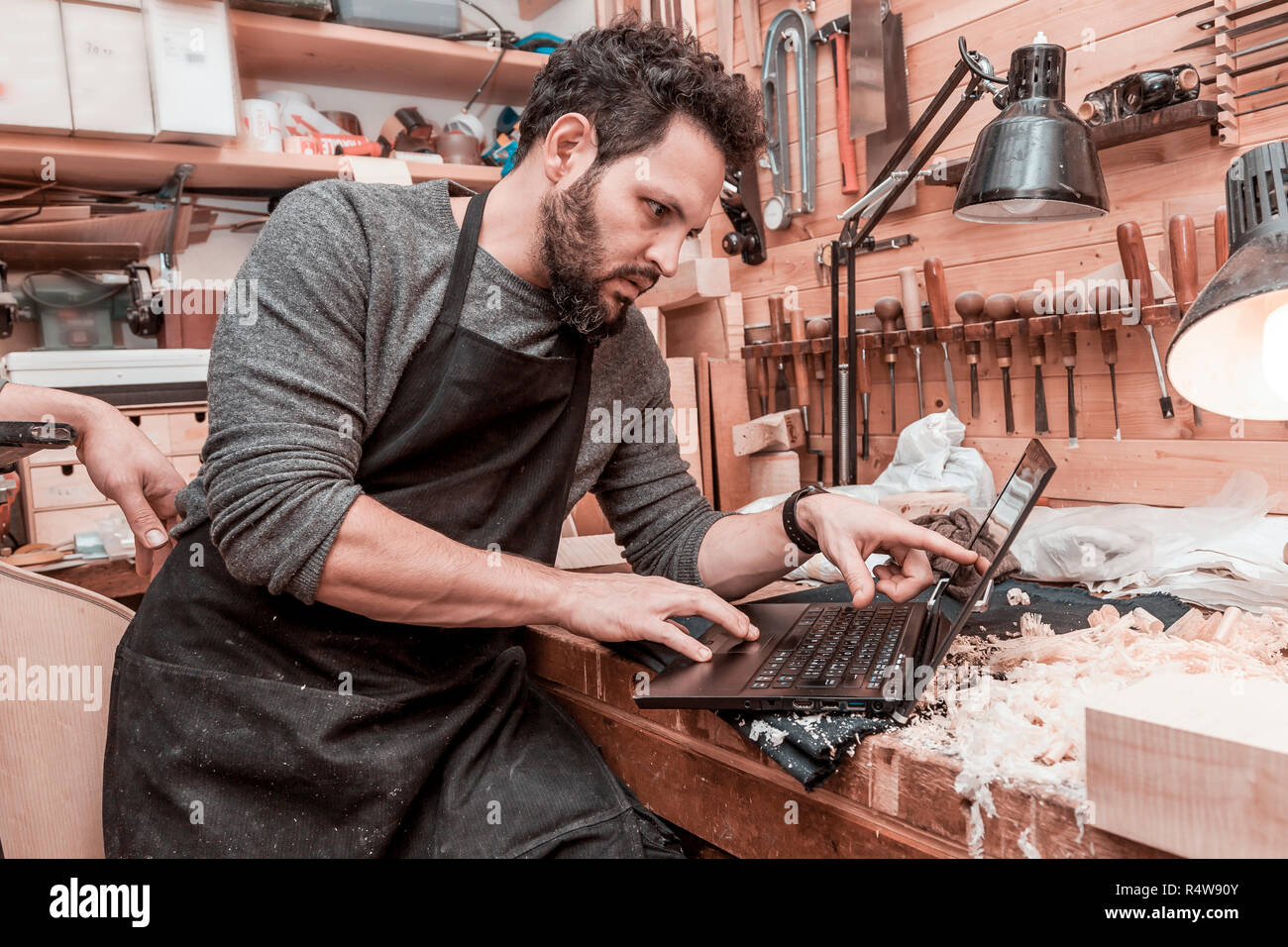 two craftsmen violinmakers checking data and measures for a new violin with computer Stock Photo