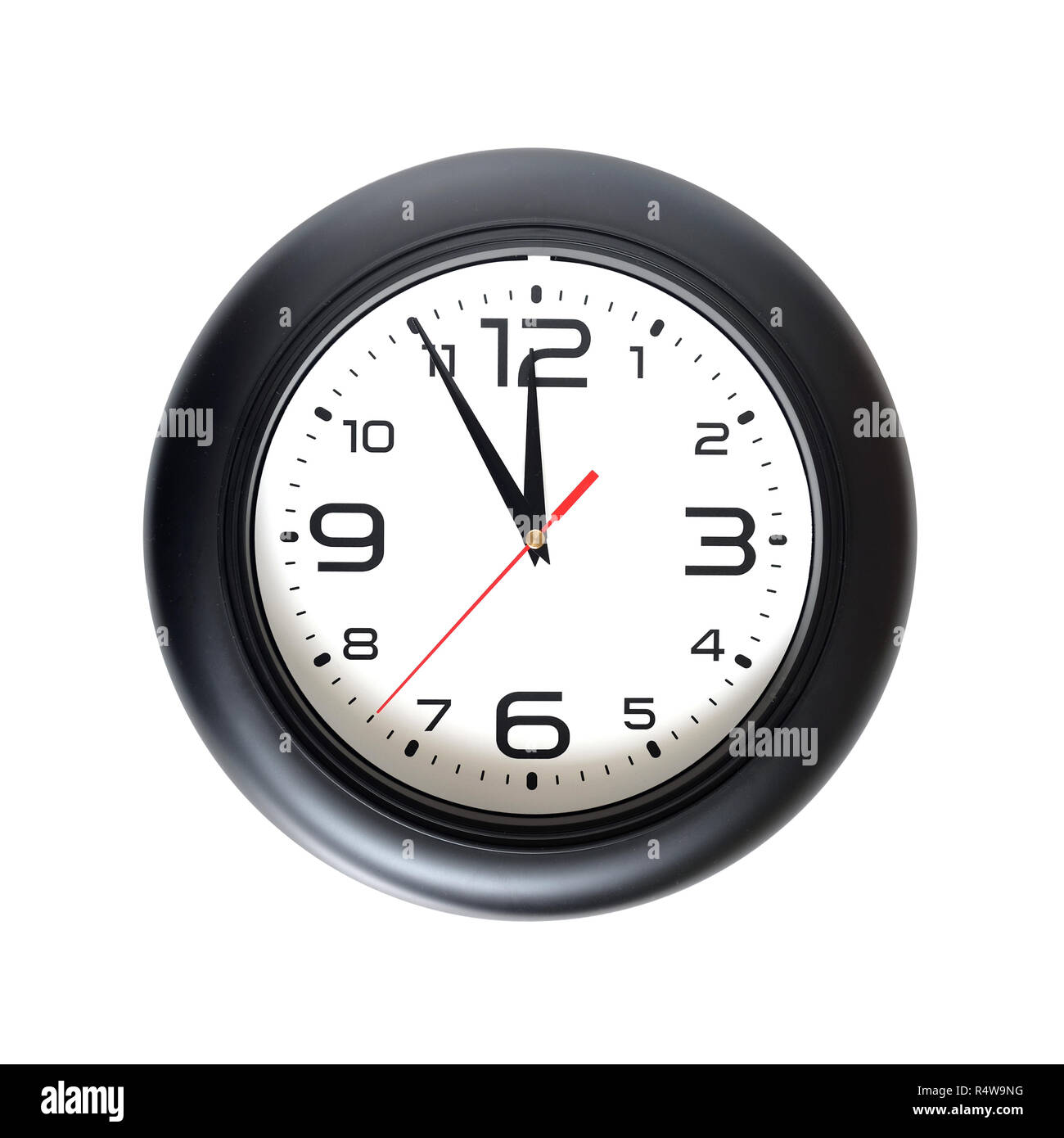 Big round wall clock with a black rim isolated on yellow background close-up and arrows showing almost twelve o'clock Stock Photo
