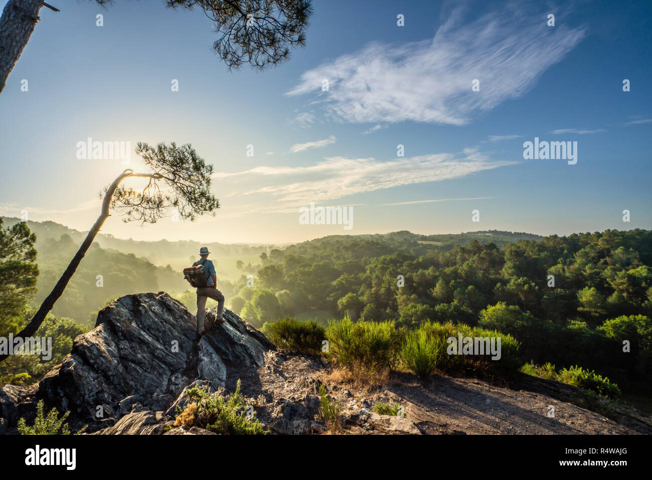 A walker on a mountain trail, looking down the valley at sunrise Stock Photo