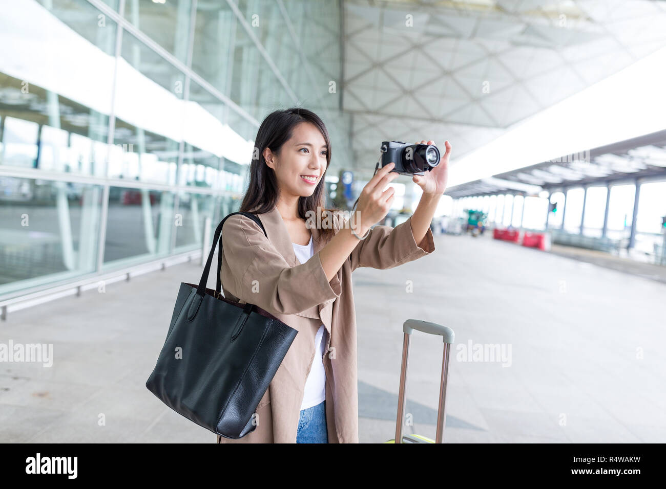 Young Woman taking photo with camera in airport Stock Photo - Alamy
