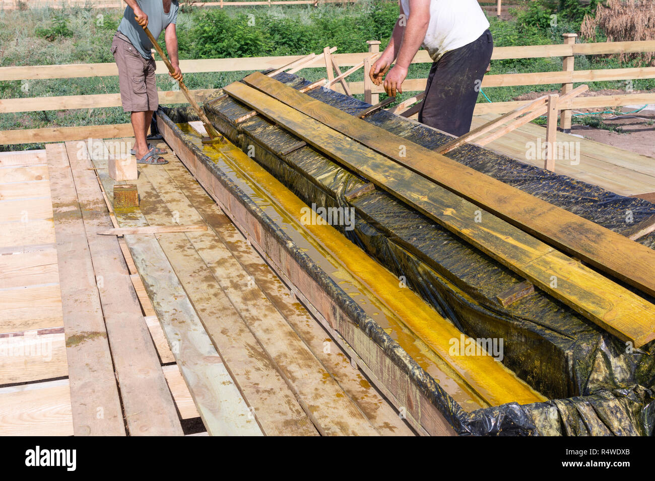 Worker at a construction site at home covers antiseptic boards. Impregnation of boards. Stock Photo