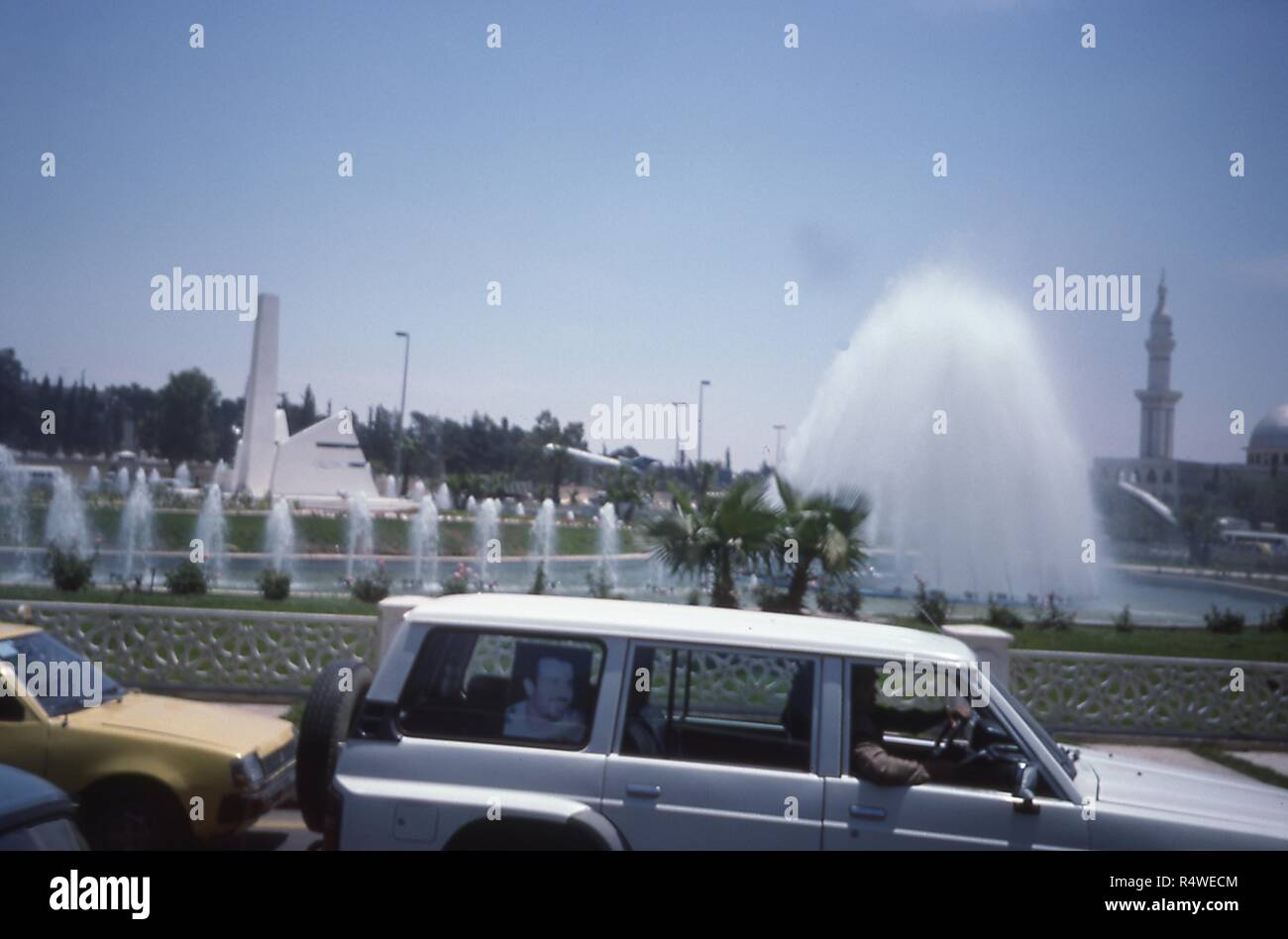 View from a vehicle in traffic driving through Damascus, Syria, June 1994. The rear window of a car in the next lane has a memorial poster of Bassel al-Assad, eldest son of President Hafez al-Assad, who died in January 1994. () Stock Photo