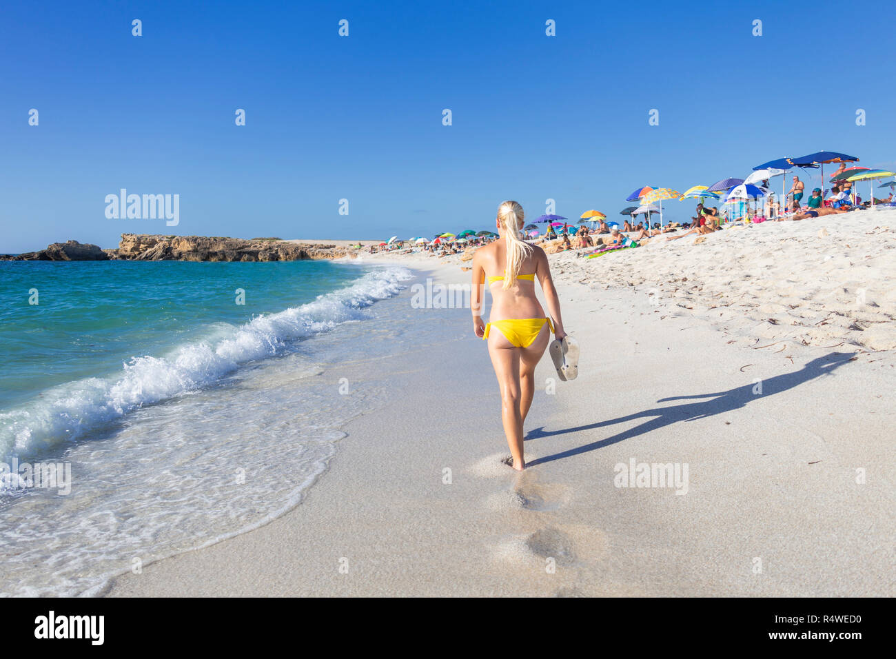 Young girl wit yellow swimsuit walks on the beach of Is Arutas, Cabras, Oristano province, Sardinia, Italy, Europe. Stock Photo