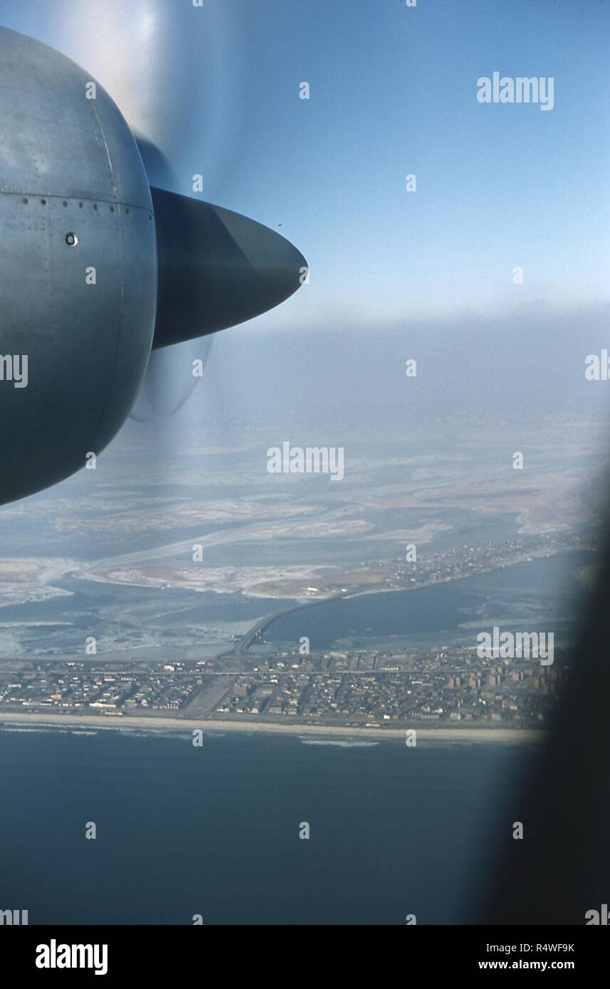 Aerial view facing north of the neighborhoods of Seaside, Rockaway Beach, and Hammels, on the Rockaway Peninsula in Queens, New York City, June, 1959. At center is the Cross Bay Boulevard Bridge, connecting the Rockaways to Broad Channel, the only inhabited island in Jamaica Bay. At left center is the promenade at Cross Bay Boulevard and Beach 94th Street. Crossing perpendicular to the promenade from left to right is the Rockaway Freeway and elevated subway tracks. At lower right is the New York City Housing Authority's Hammel Houses apartment building complex. At bottom edge is the Atlantic O Stock Photo