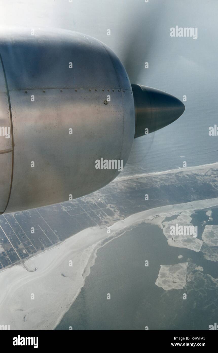 Aerial view facing south of the Rockaway Peninsula, in the borough of Queens, New York City, June, 1959. The water of Jamaica Bay is covered in ice floes hugging the snowy coastline across the lower foreground. The Atlantic Ocean is at upper right. At upper left foreground is the engine of a Swissair DC 7C HB IBP 'Seven Seas' aircraft. () Stock Photo