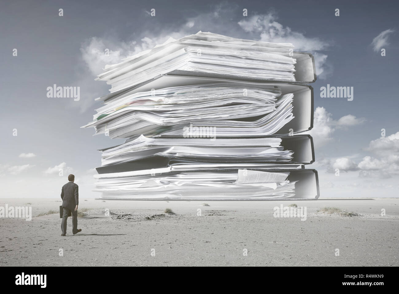 A businessman is walking towards a surreal mountain of paperwork Stock Photo