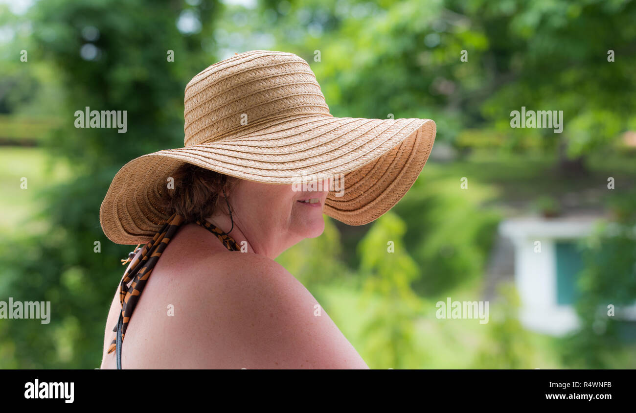 Lady wearing a sun hat, face partially hidden.  Ultra violet sun ray protection and blocker on a bright warm day. Stock Photo