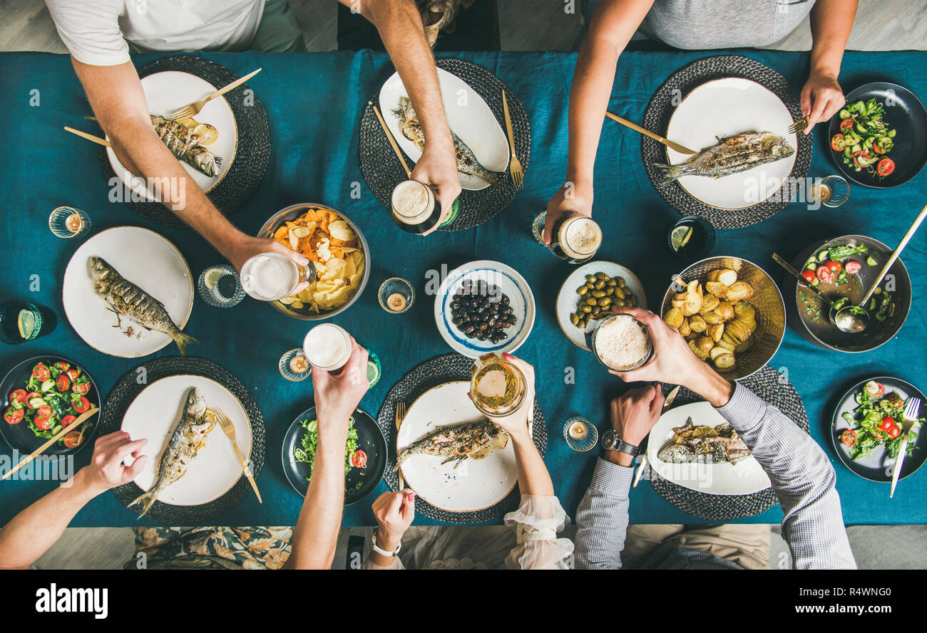 Flatlay of people eating fish, drinking beer and celebrating together