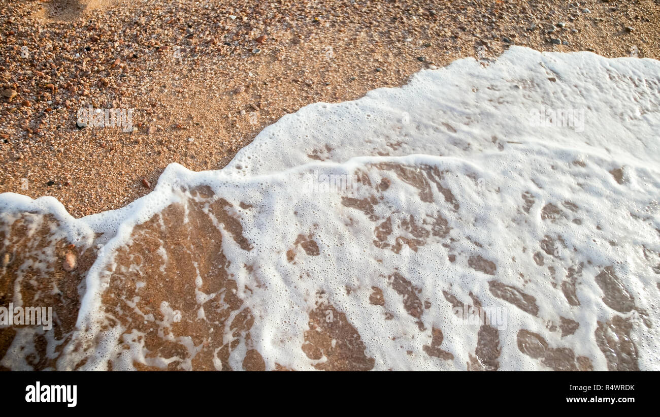 Closeup photo of ocean waves rolling over sandy beach at sunset Stock ...