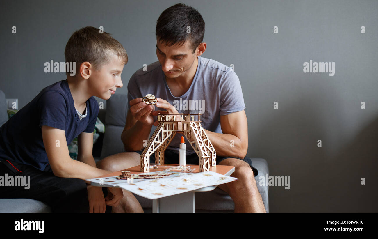 Young boy assembling wooden constructor with his father. Eco building toy set Stock Photo
