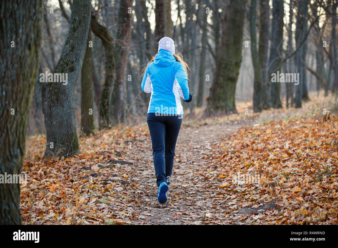 Young slim woman running in cold weather in late fall. Rear view jogging image Stock Photo