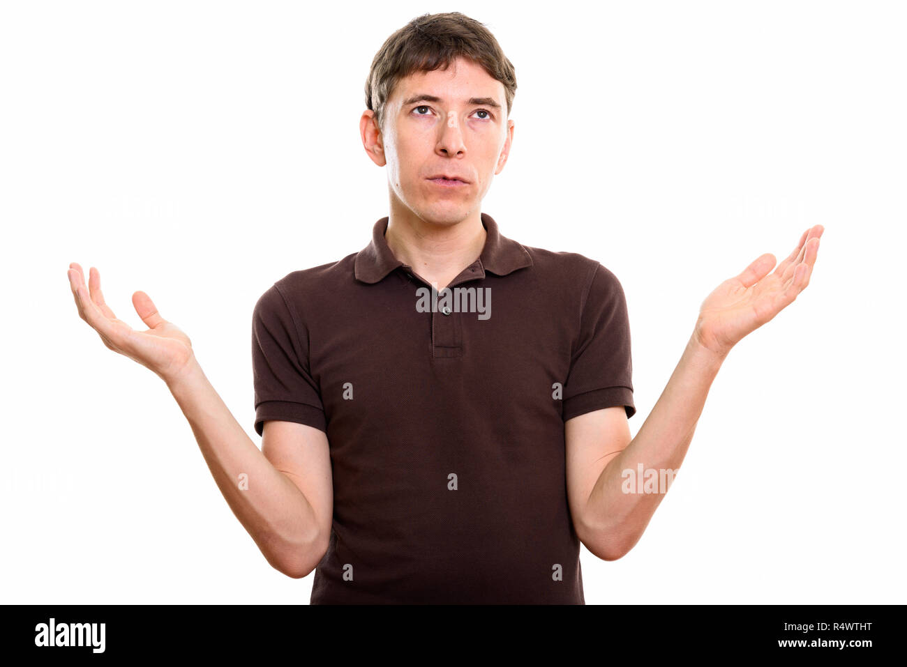 Studio shot of man looking confused with both arms raised Stock Photo