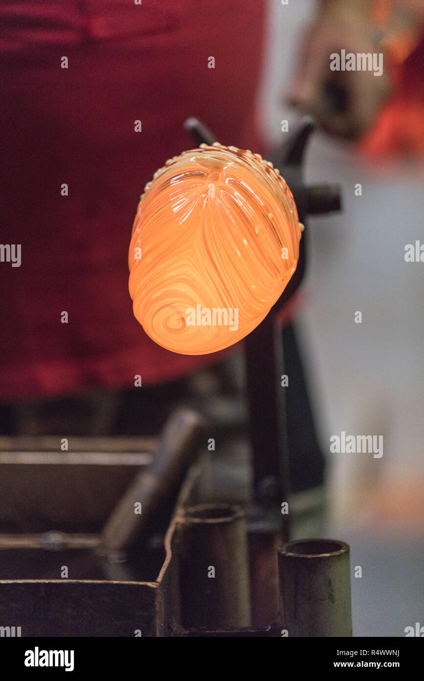 glass blower carefully forming hot glass to a decorative vase, germany
