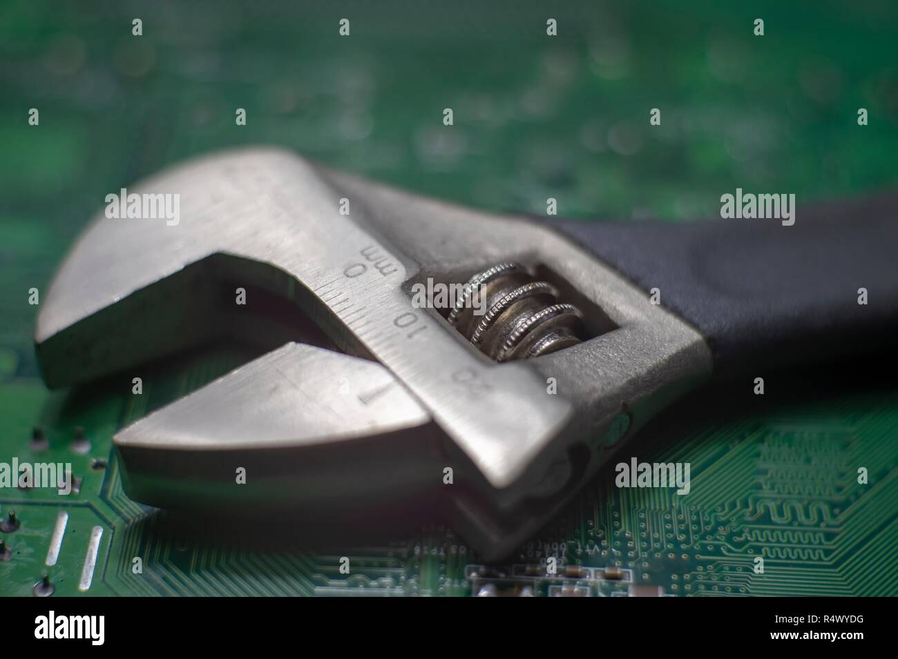 Close up adjustable spanner wrench on a green electronics board, use the right tool concept image Stock Photo