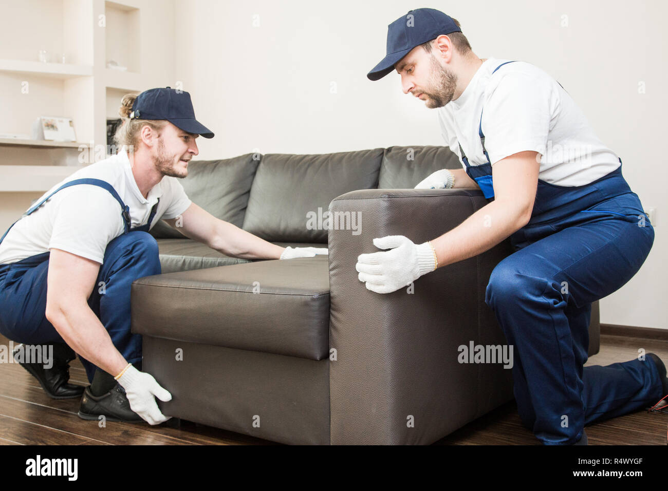 Delivery man move furniture carry sofa for moving to an apartment.  professional worker of transportation, male loaders in overalls Stock Photo  - Alamy