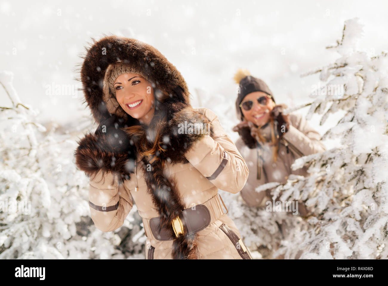 Two beautiful happy female friends taking a walk while its snowing ...