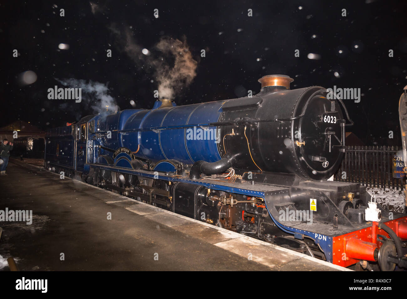 Vintage UK steam locomotive King Edward II, front view, alongside platform at Kidderminster SVR station, in the dark, snow flakes falling. Stock Photo