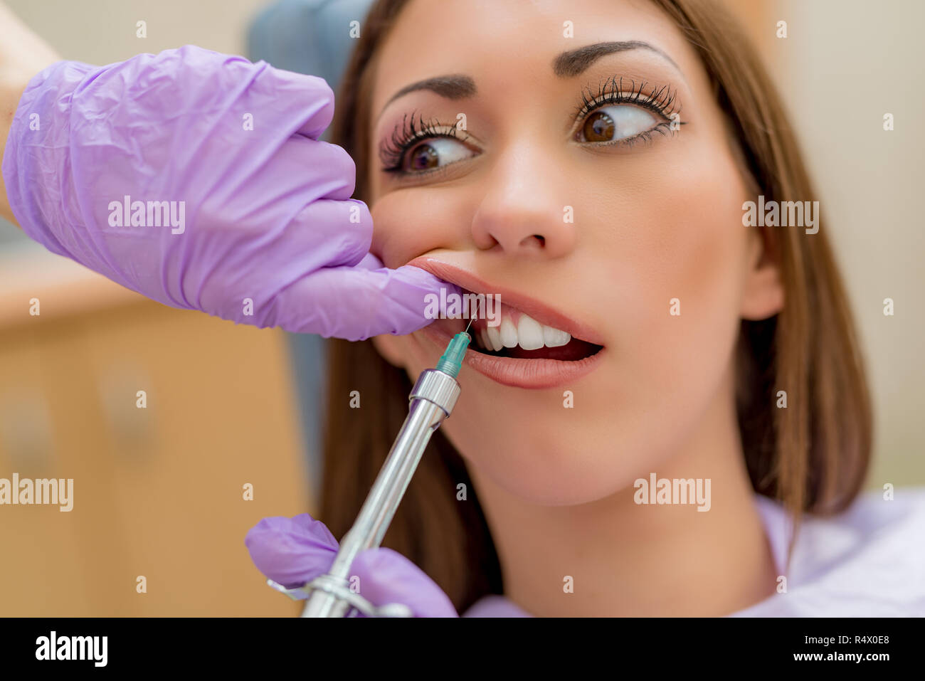 Dentist giving an injection of anesthesia to the female patient before