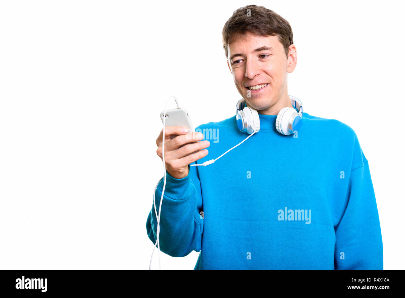 Happy man smiling while wearing headphones around neck and using Stock Photo