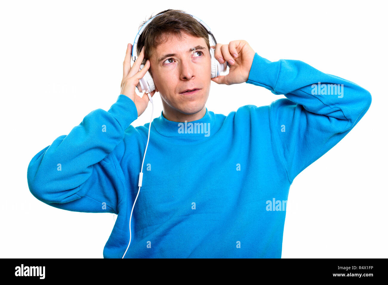 Thoughtful man listening to music while holding headphones with  Stock Photo
