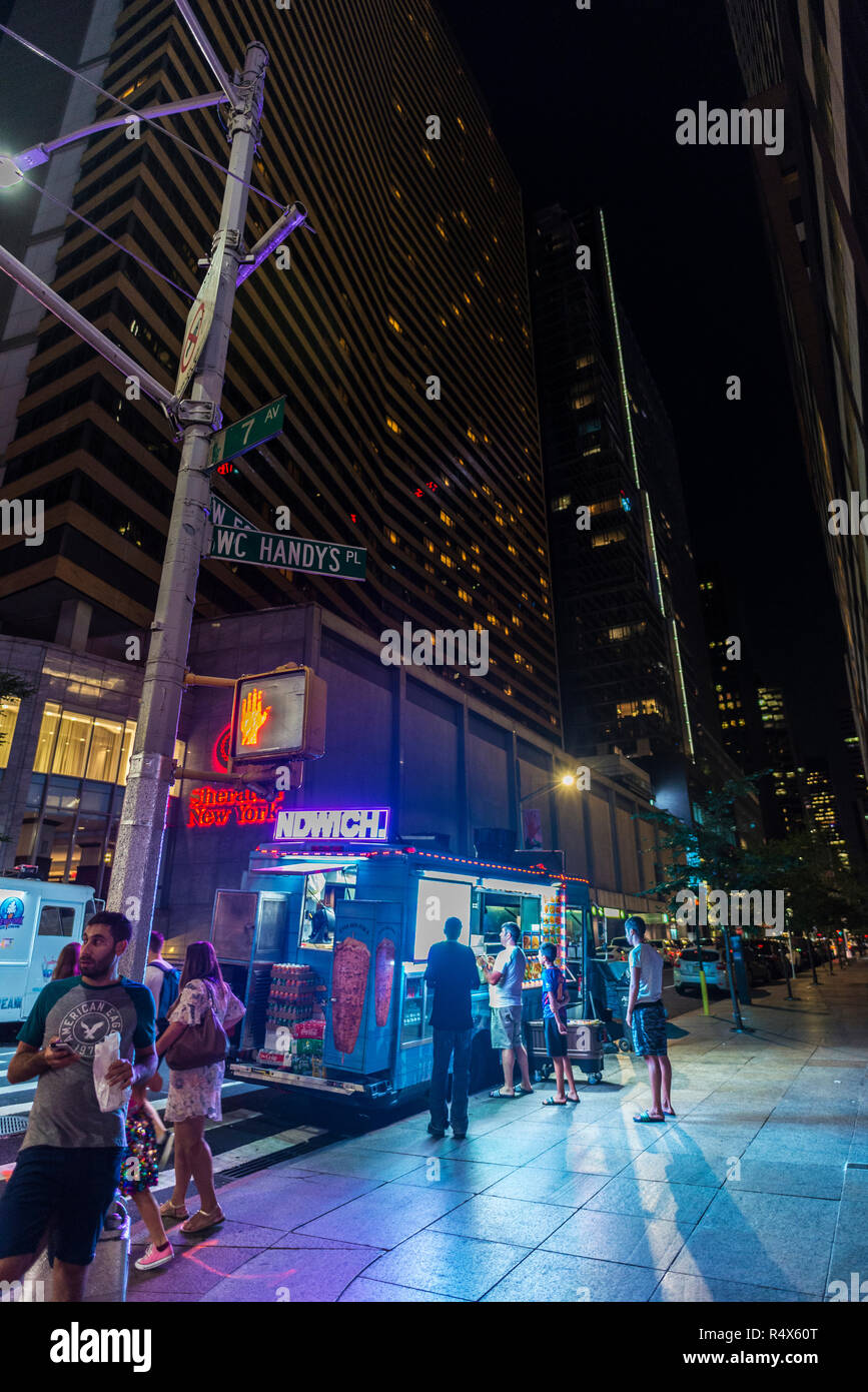 New York City, USA - July 30, 2018: Vendor in its food truck at night on Seventh Avenue (7th Avenue) with people around in Manhattan in New York City, Stock Photo