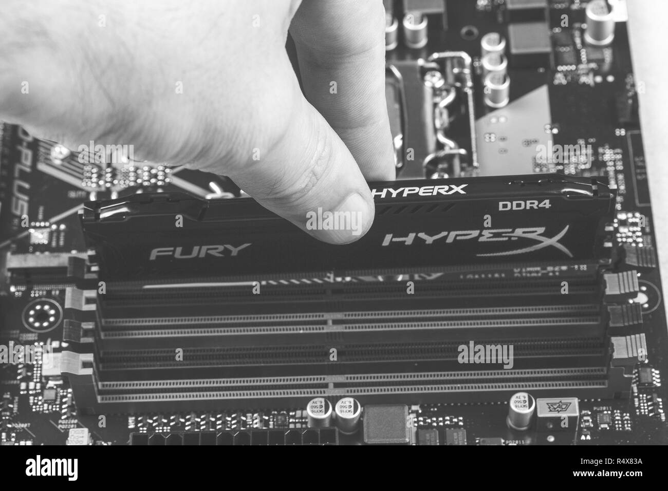 Maykop, Russia - November 9, 2018: man installs an DDR 4 DIMM 16 Gb Kingston HyperX Fury Memory RAM Module in the slot on the motherboard closeup, bla Stock Photo