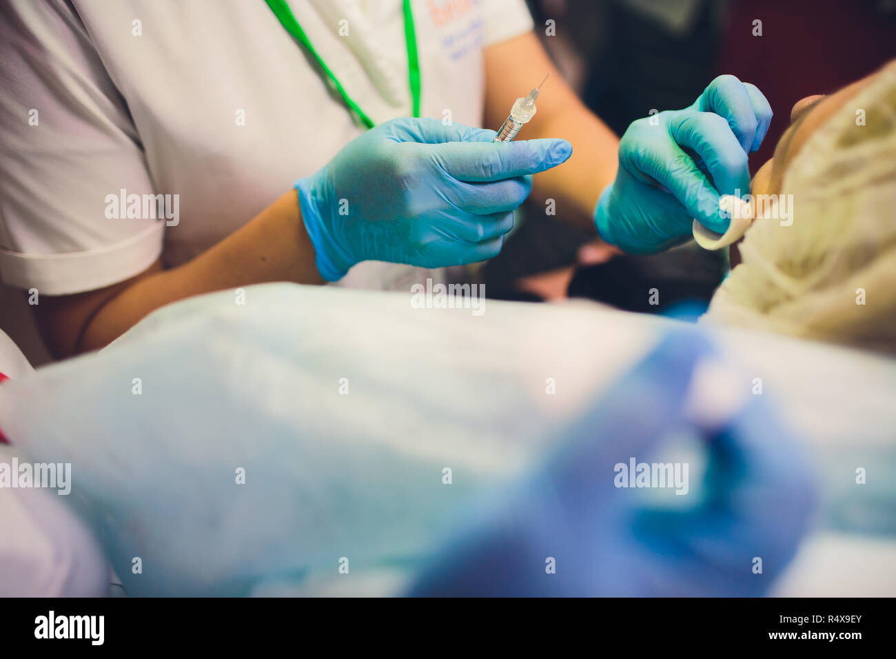 Close up of female doctor's hands putting on blue sterilized surgical