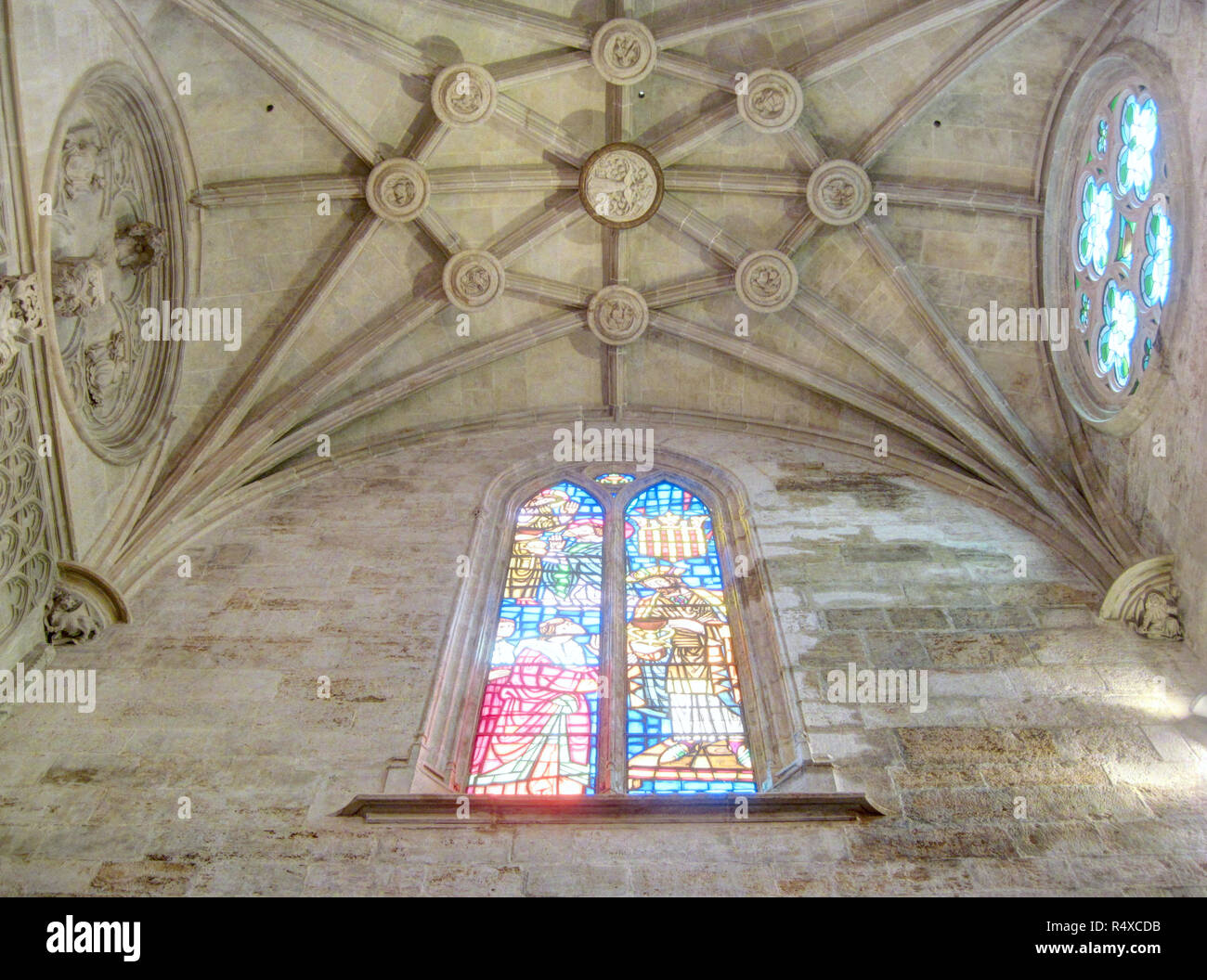 A pointed arch stone window with a stained glass decoration and lights