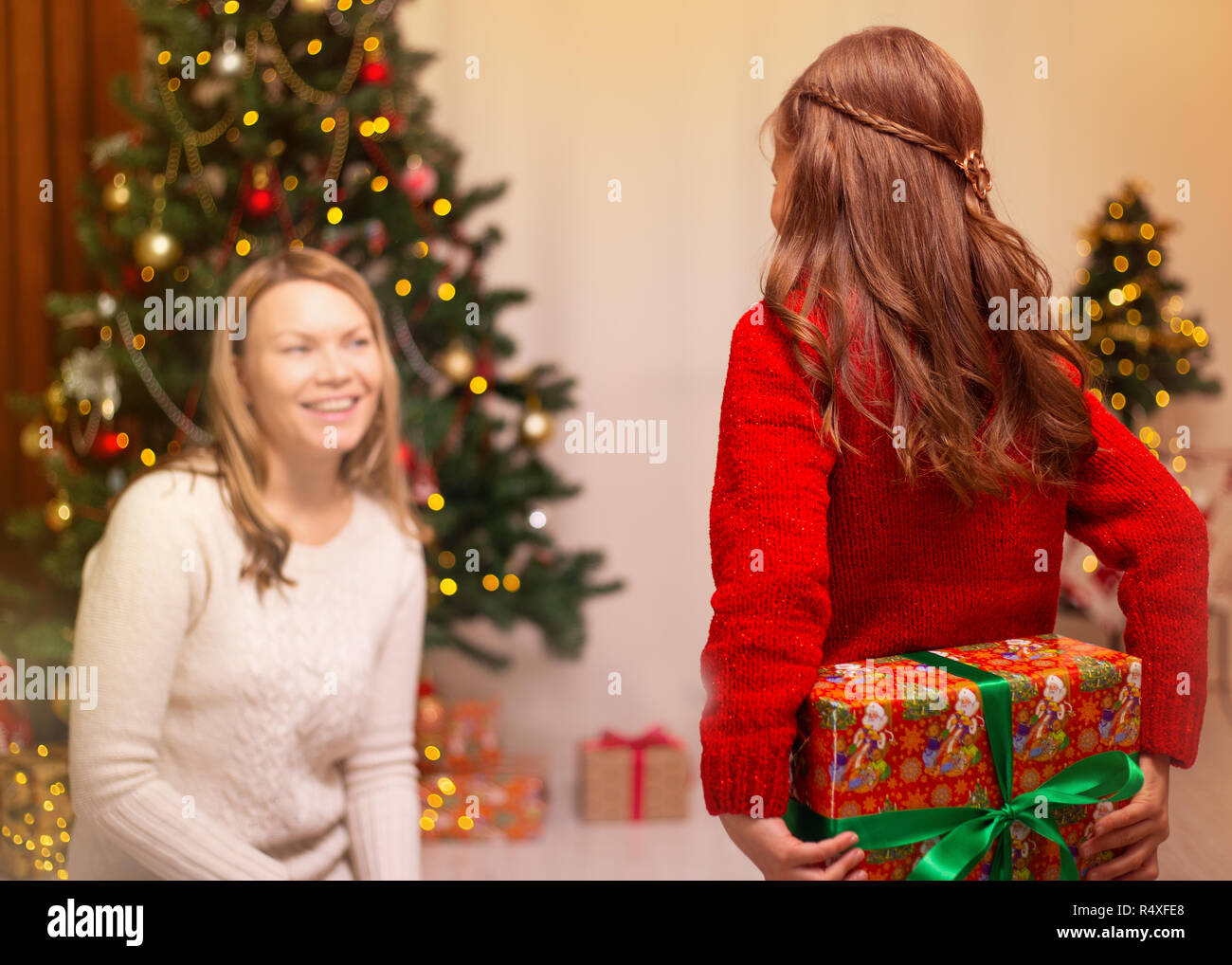 Cheerful mom and her cute daughter girl exchanging gifts. Merry
