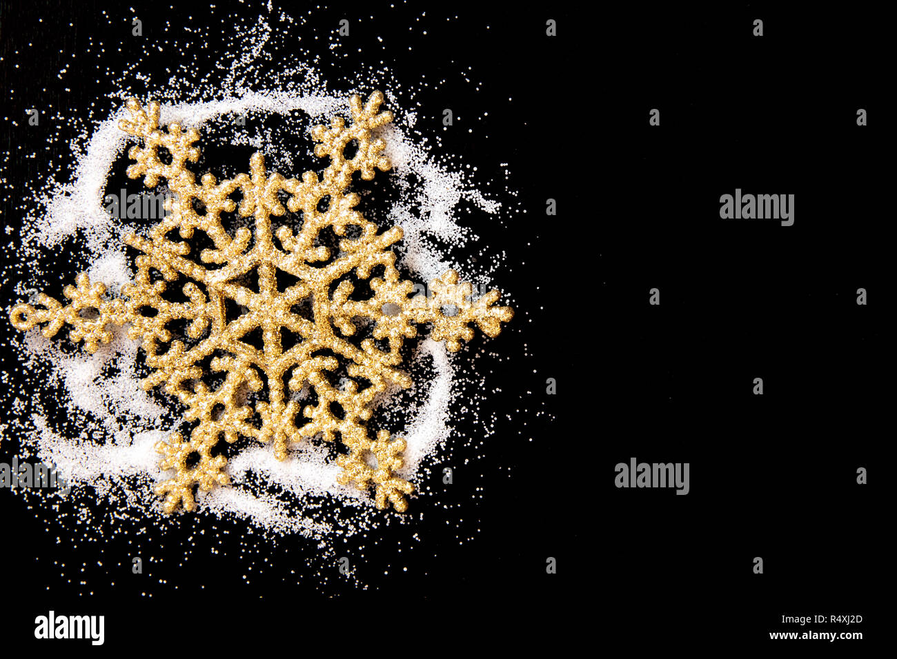 Snow white salt powder spot cloud on left side on black background. Golden snowflake toy. New year and Christamas concept with place for text. Copy space. Stock Photo