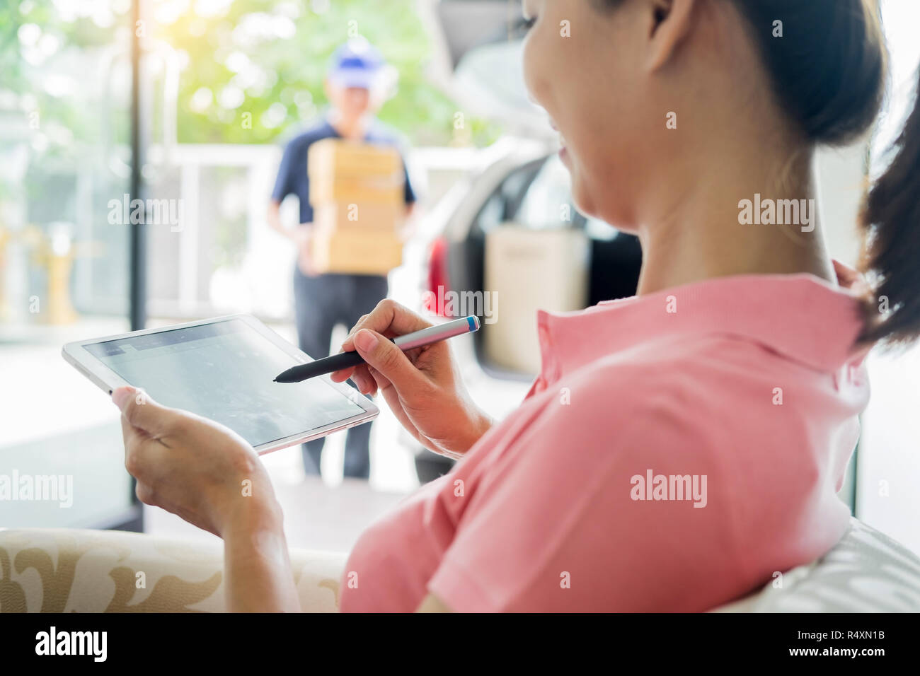 woman courier holding a parcel Shipping Mail appending signature signing delivery note after receiving package from delivery man Stock Photo