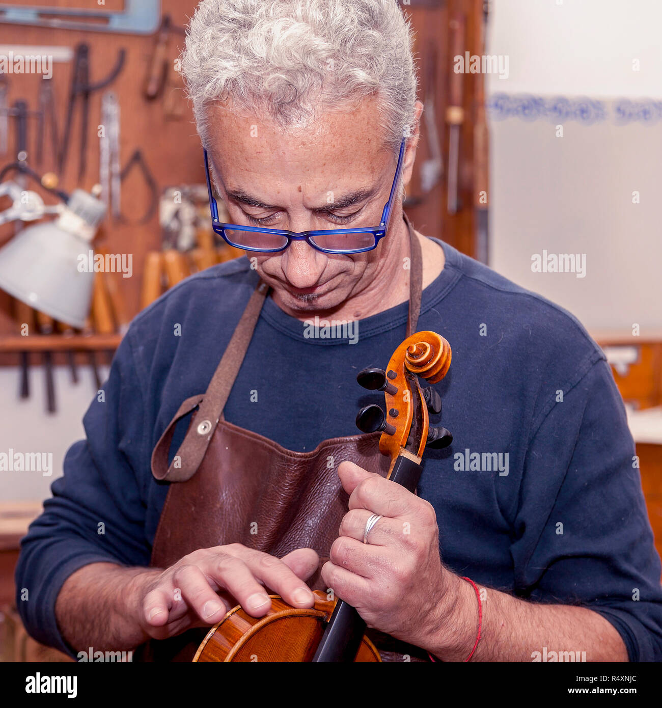 portrait of mature violin maker while testing the violins in his