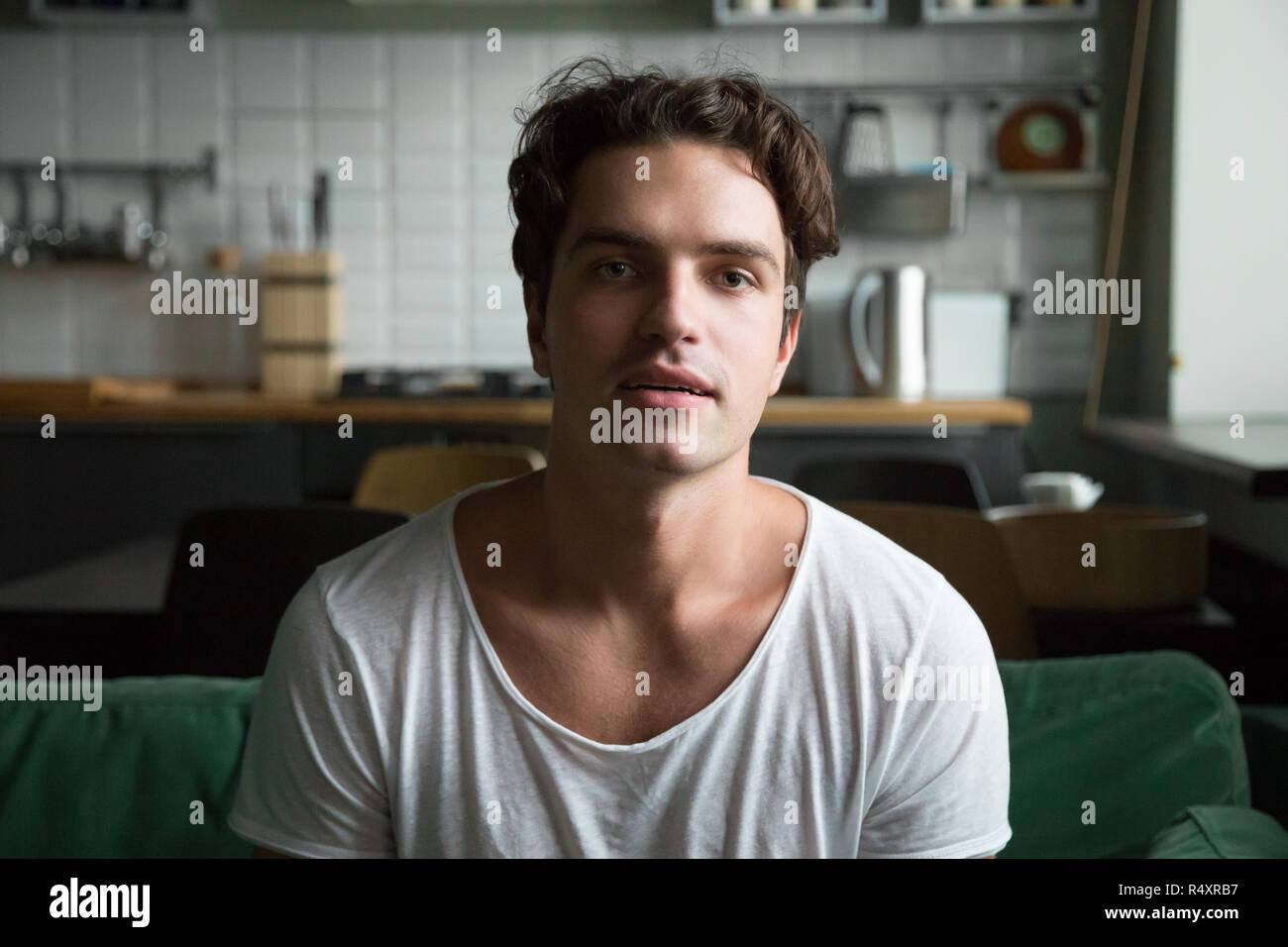 Handsome young man sitting on couch looking at camera Stock Photo
