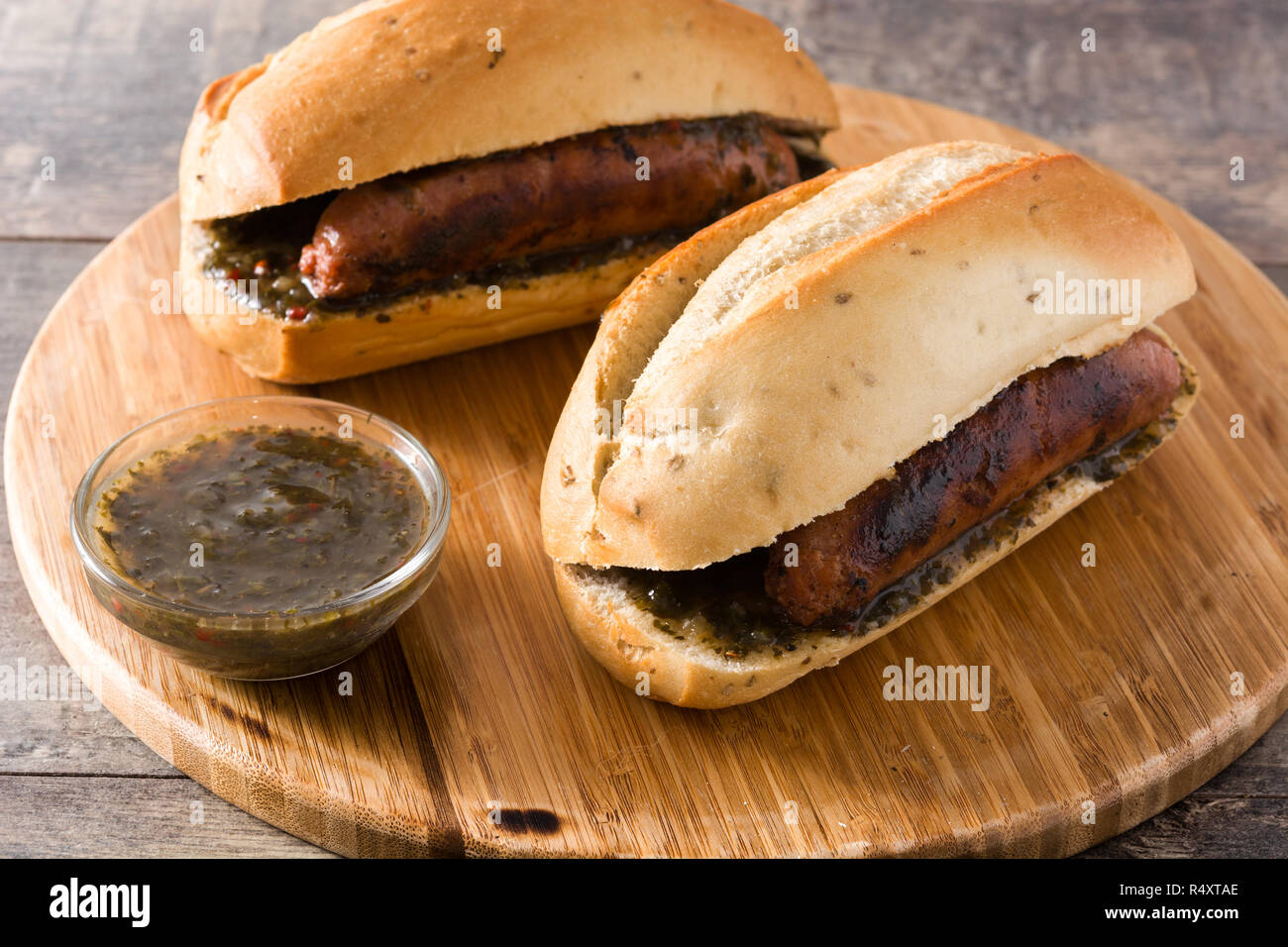 Choripan. Traditional Argentina sandwich with chorizo and chimichurri sauce on wooden table Stock Photo
