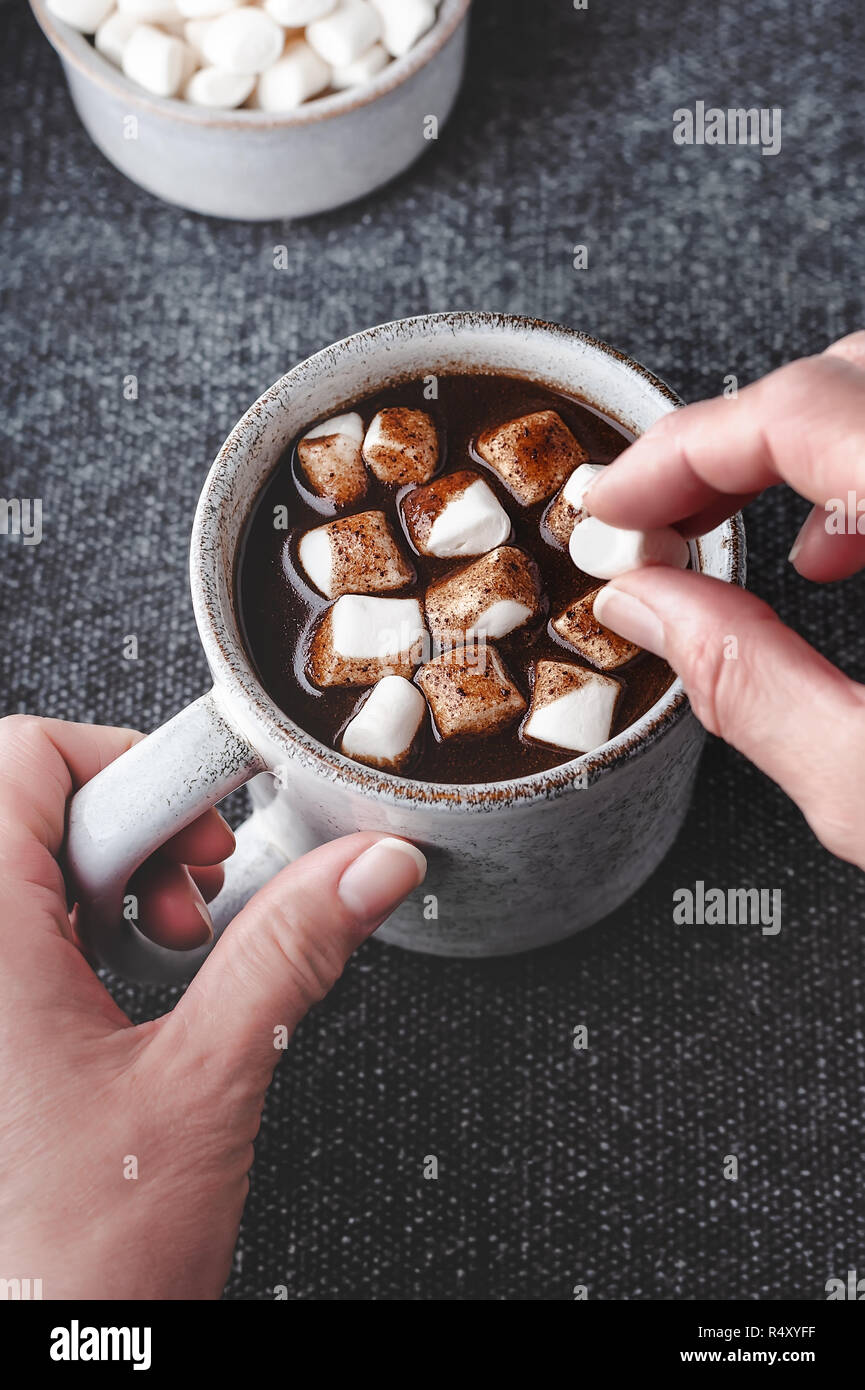 A woman adds marshmallows to a cup of hot carob, a caffeine free alternative to chocolate. Stock Photo