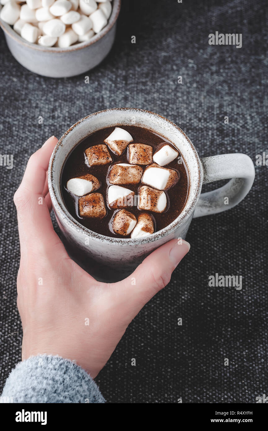 A woman reaches for a cup of hot carob (naturally caffeine free) topped with marshmallows. Stock Photo