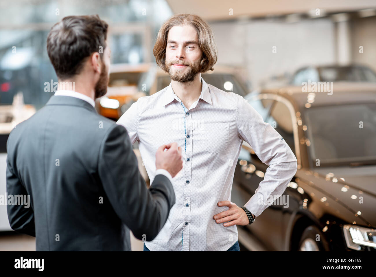 Car salesman helping a young male client to make a decision talking