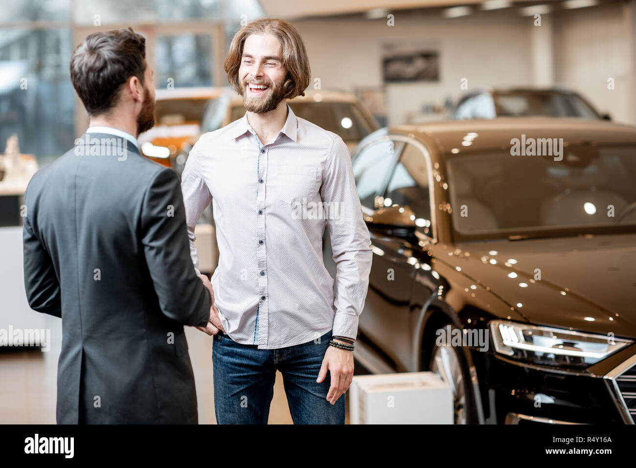Car salesman helping a young male client to make a decision talking