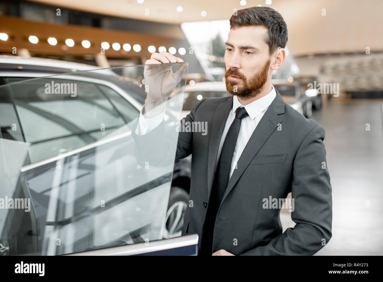Businessman looking on the frameless window of a luxury car in the showroom Stock Photo Alamy