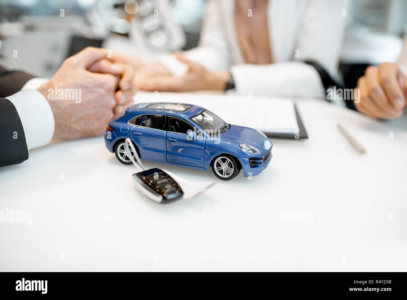 Close-up of a toy car with keychain and clients hands on the table of the car showroom Stock Photo