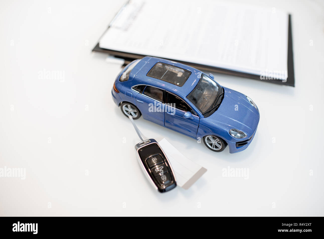 Close-up of a toy car with keychain and documents on the white table Stock Photo