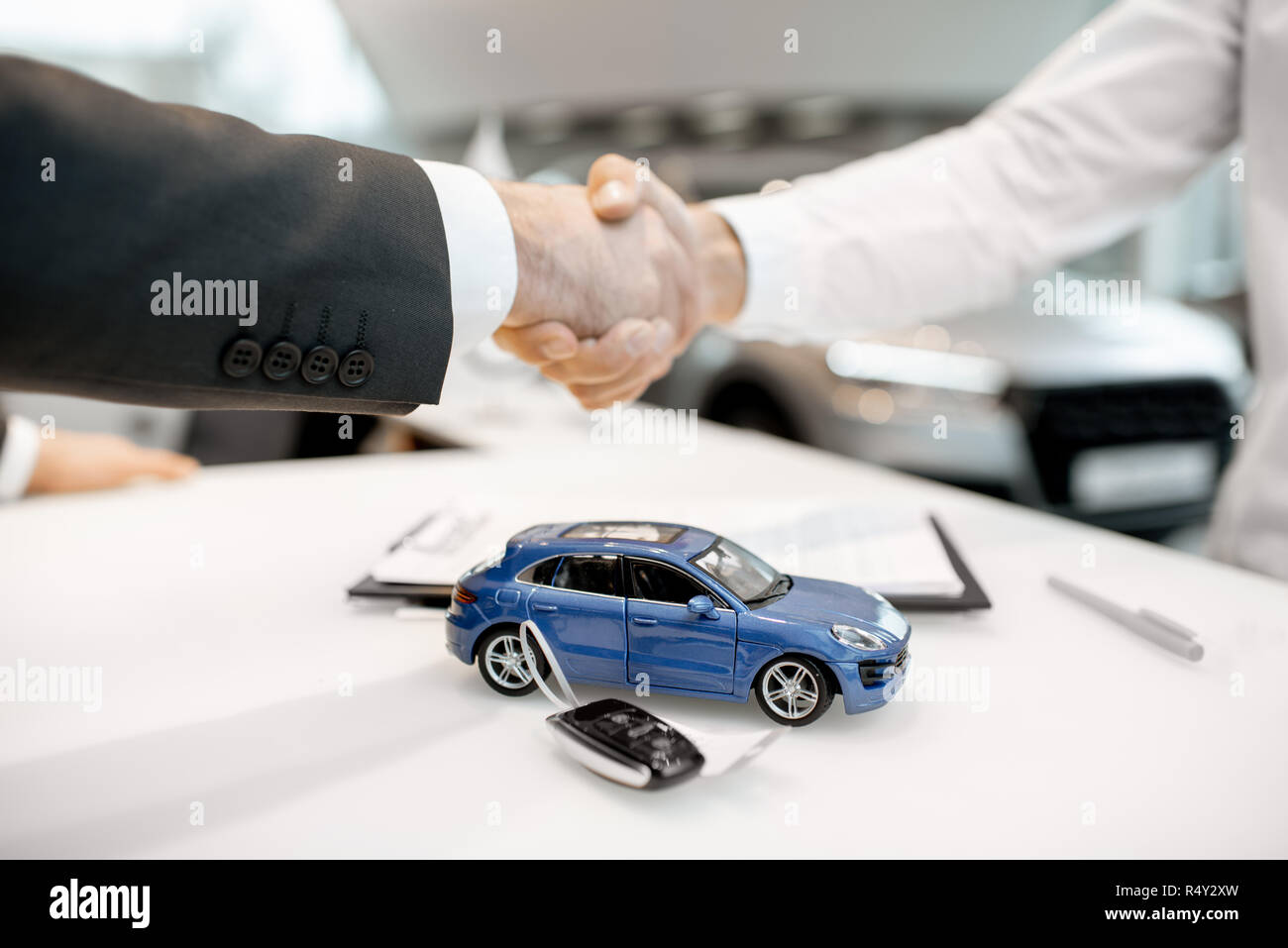 Close-up of a handshake at the table with toy car and keys. Car buying concept Stock Photo